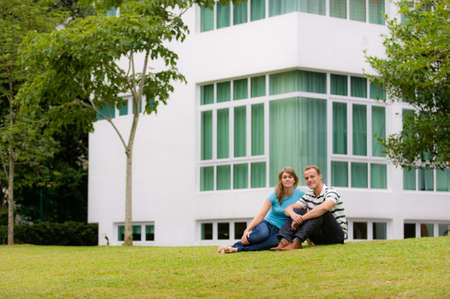 A young couple sitting in garden of their houseの写真素材