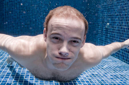 An underwater shot of a man in a swimming pool holding his breath