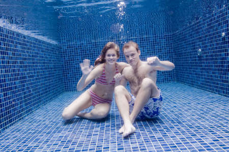 A young couple underwater in a poolの写真素材