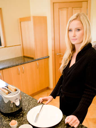 A young attractive woman making breakfast in the kitchenの写真素材