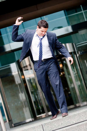 A young businessman walking out of building about to smash phoneの写真素材