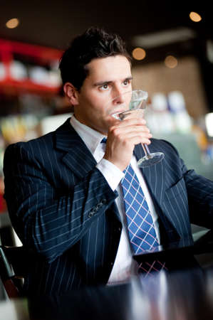 A young handsome businessman sitting in a bar drinking a martiniの写真素材