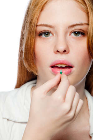 A young woman holding a small pill on white backgroundの写真素材