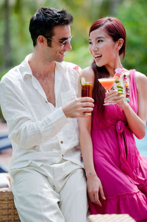 An attractive couple having drinks by the pool on vacationの写真素材