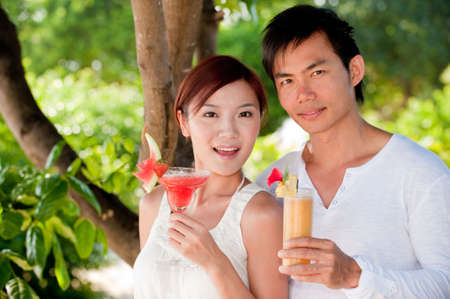 An attractive young couple relaxing on holiday with drinksの写真素材