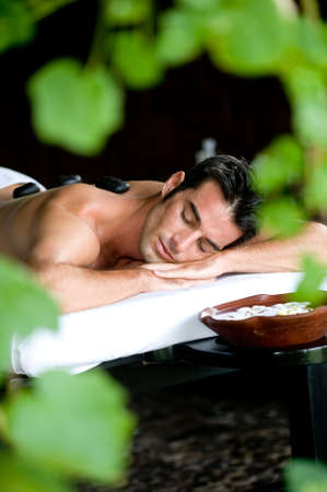 A good-looking man relaxing with hot stones on back before massageの写真素材