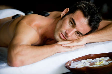 A good-looking man relaxing with hot stones on back before massageの写真素材