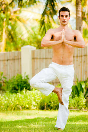 A young man doing yoga in the gardenの写真素材