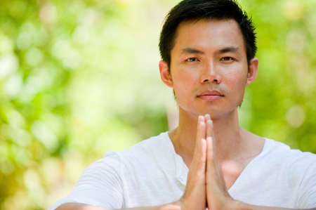 A young Chinese man meditating outsideの写真素材