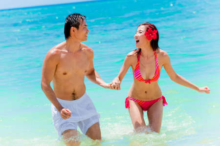 An attractive Asian couple in the sea playing aroundの写真素材