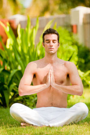 A young man doing yoga in the gardenの写真素材