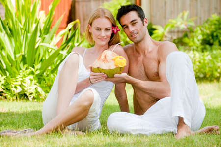 A couple sitting in the garden with a fresh young coconut drinkの写真素材