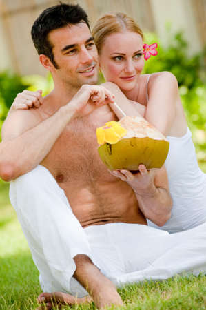 A couple sitting in the garden with a fresh young coconut drinkの写真素材