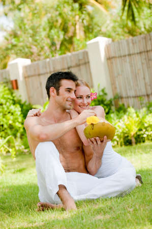 A couple sitting in the garden with a fresh young coconut drinkの写真素材