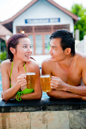 Asian Couple Drinking Beer in Pool