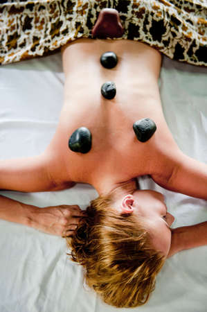 A woman having hot stones massage therapyの写真素材
