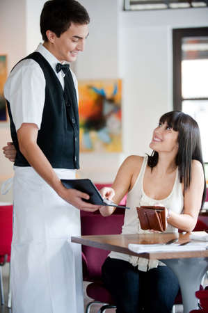 A young and attractive woman paying the bill at a restaurantの写真素材