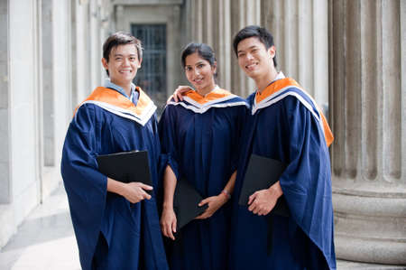 A group of graduates holding their mortar board in their hands and standing in a hallway