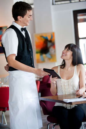 A young and attractive woman paying the bill in a restaurantの写真素材