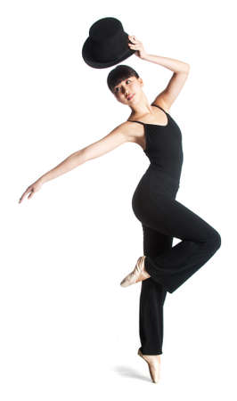 A young attractive ballerina poses with a top hat against white background
