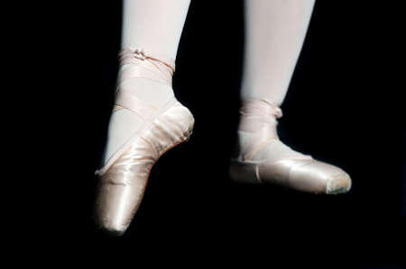 A pair of feet wearing ballet slippers posing on black backgroundの写真素材