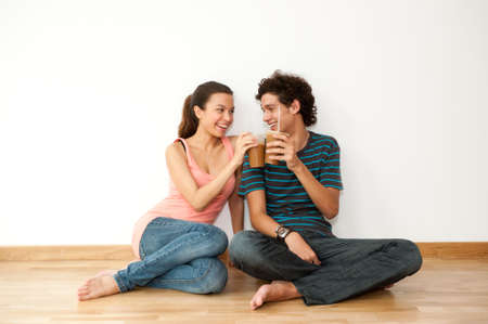 A young and attractive asian woman talking on the phone and using her laptop in her new homeの写真素材
