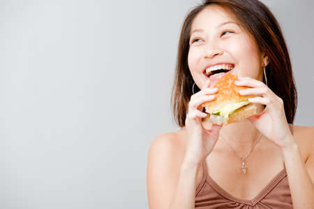 A good looking woman having a sandwich against white background