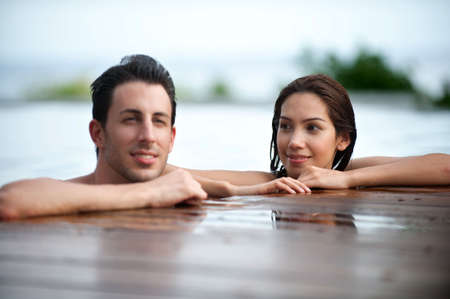 An attractive caucasian couple relaxing in an outdoor pool togetherの写真素材