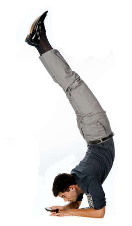 An attractive athletic businessman doing a handstand while using his mobile phone against white...