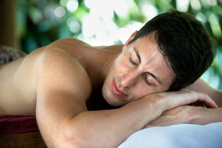 An attractive caucasian man lying down on a massage bed at a spaの写真素材