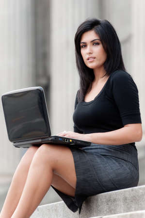 A young attractive Asian businesswoman sitting outside with laptopの写真素材