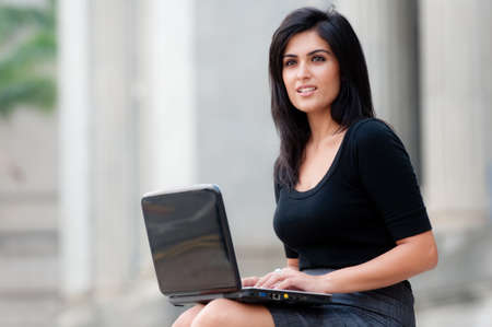 A young attractive Asian businesswoman sitting outside with laptopの写真素材