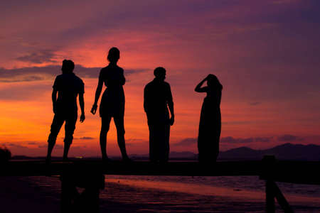 Four friends enjoying the sunset on a jettyの写真素材