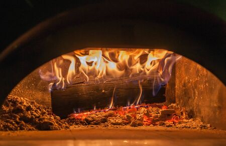 Wood burns in pizza oven close up on flames and burning embersの写真素材