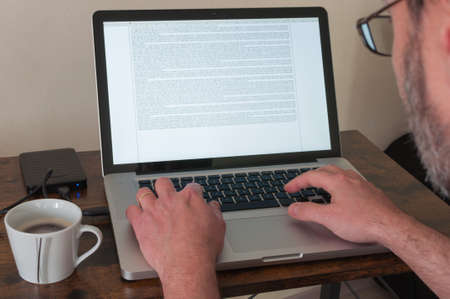 Man working at home on a laptop typing a text on the keyboard