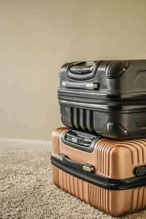 Two hard shell suitcases stacked on top of each other on a textured carpet against a plain wall.