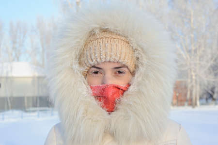 Girl with hoarfrost on the eyes. The white fur coat and hood. Very cold, frost. His face is closed,...