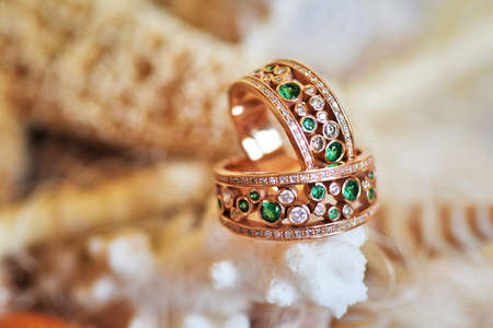 Vintage wedding rings of gold, diamonds and emeralds. Lie on the scenery of starfish and seashellsの写真素材