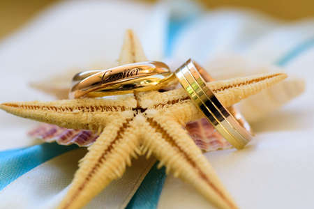 Gold wedding rings are lying on the seastarの写真素材