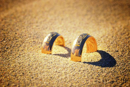 Gold wedding rings are on the sand. Silhouette of newlyweds are recognized in the rings.の写真素材