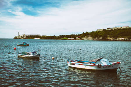 HAVANA, CUBA - May 15, 2016: Seafront Malecon in Havana. Boats in the Atlantic Ocean on a sunny day. View to lighthouse and El Morro Castle from the seafront. Fortress guarding the entrance to Havana bay.のeditorial素材