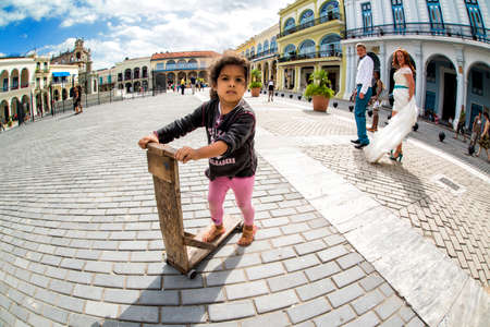 HAVANA, CUBA - May 17, 2016: Little girl is riding on a square at sunny day. Couple is walking on the street in the center of Havana.のeditorial素材