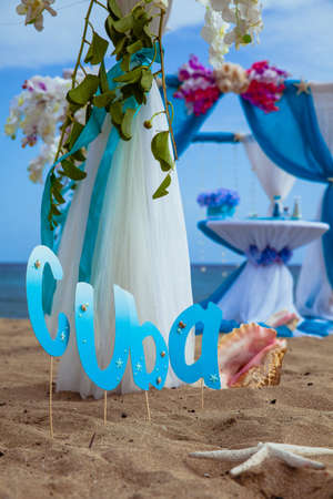 Accessory kit for a wedding is on the shores of the Caribbean Sea. Arch is decorated with curtains and flowers.の写真素材
