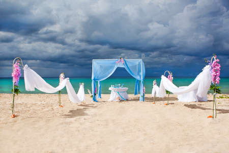 Accessory kit for a wedding is on the shores of the Caribbean Sea. Arch is decorated with curtains and flowers.の写真素材