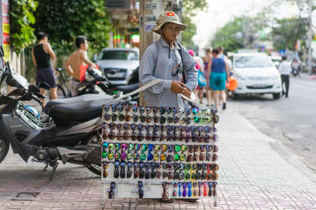 NHA TRANG, VIETNAM - JUNE 19, 2016: Asian man is selling cheap fake sunglasses on the street on Vietnam in the middle of the dayのeditorial素材