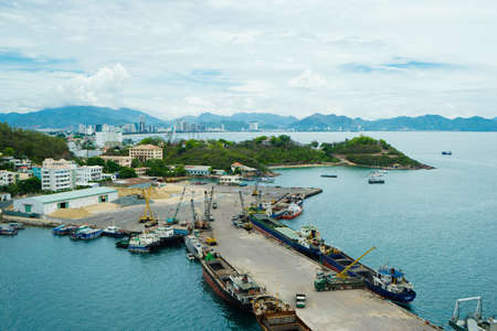 NHA TRANG, VIETNAM - JUNE 22, 2016: View of seaport with the cargo ships, harbor under construction and coastal park against mountainsのeditorial素材