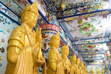 NHA TRANG, VIETNAM - JUNE 23, 2016: Internal furniture of the Buddhist temple. Gold statues of Buddha inside. Walls are painted with multi-colored drawings.のeditorial素材