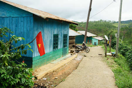 NHA TRANG, VIETNAM - JUNE 23, 2016: Small wooden house with flag in a village of tropical jungle. In the yard there is a motorcycle and nobody's aroundのeditorial素材