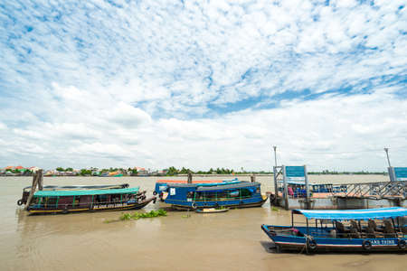HO CHI MINH CITY, VIETNAM - JUNE 26, 2016: Empty boats for tourists are parked near the coastline of the river with muddy water on a mooring at vietnamese village. View to the pier at summer sunny dayのeditorial素材