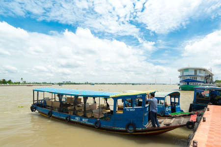 HO CHI MINH CITY, VIETNAM - JUNE 26, 2016: Empty boat for tourists is parked near the coastline of the river with muddy water on a mooring at vietnamese village. View to the pier at summer sunny dayのeditorial素材